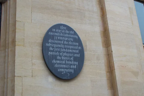 石牆上標示 1897 年在 Cavendish Laboratory 發現電子的圓形紀念牌