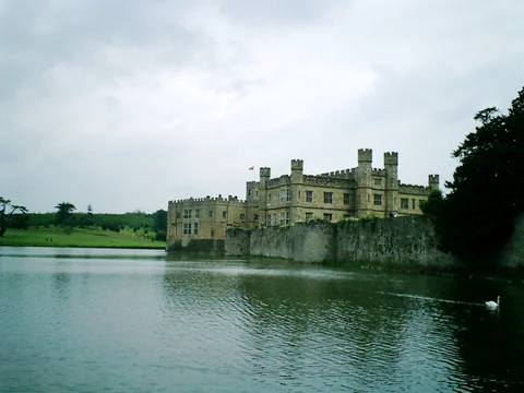 Leeds Castle 位在湖邊，天空陰 cloudy，水面有天鵝。