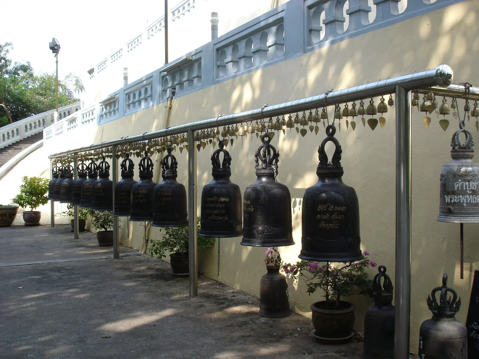 曼谷寺廟牆邊的黑色鐘與庭院。