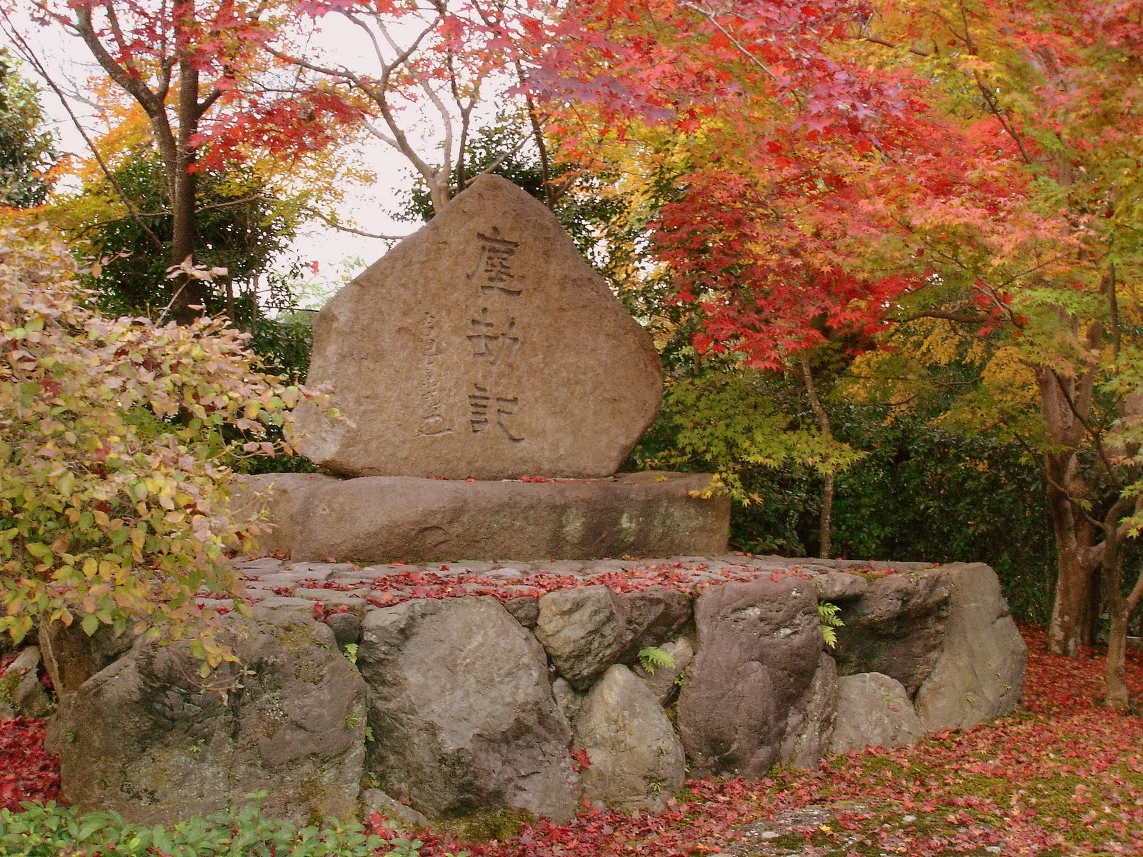 嵯峨嵐山駅石碑旁有紅、黃、綠色楓葉。
