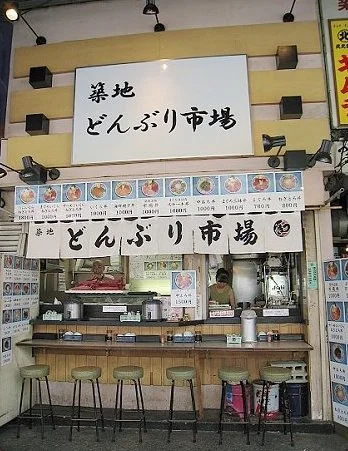 築地どんぶり市場店面，櫃檯上方掛著菜單照片與招牌。