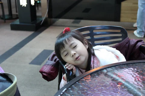 小朋友靠在機場桌邊等待。