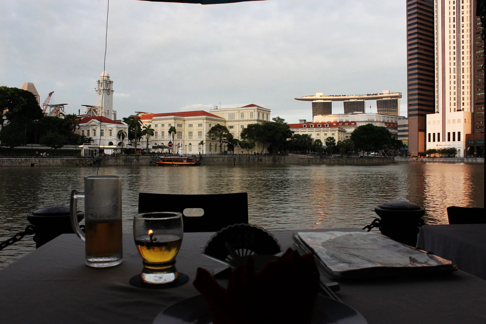新加坡河畔餐桌上的 Tiger Beer，對岸建築在背景中。