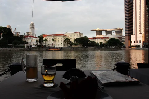 新加坡河畔餐桌上的 Tiger Beer，對岸建築在背景中。