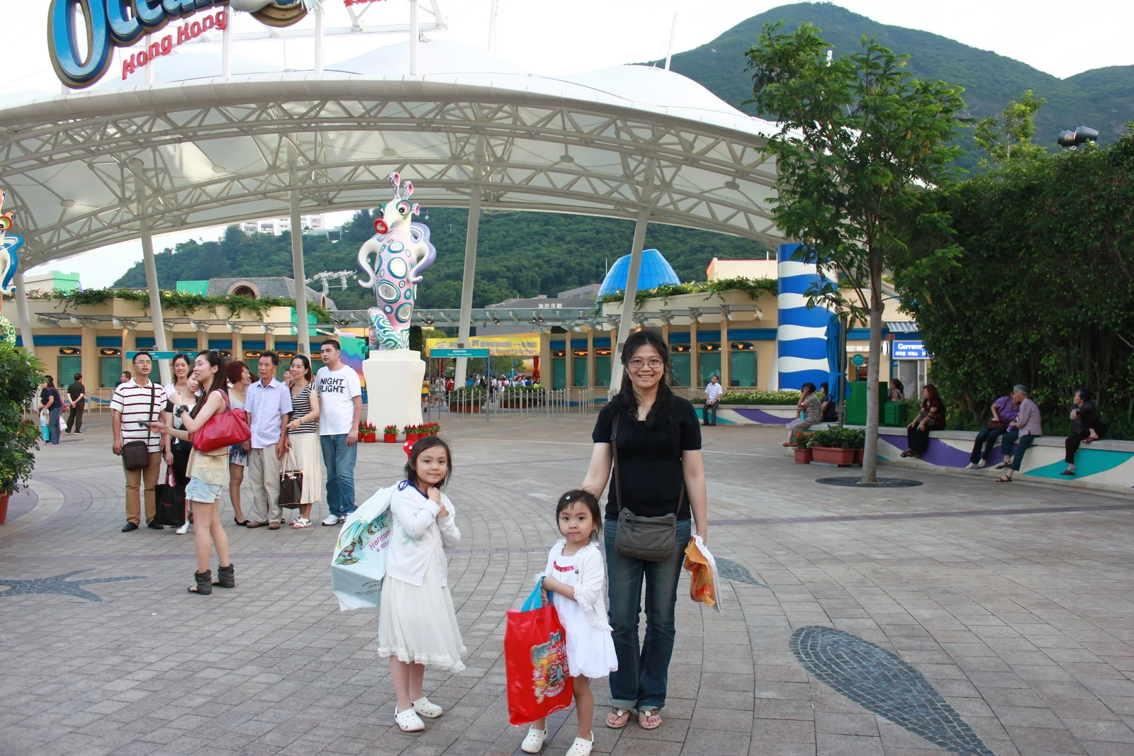 家人帶著紀念品袋走在海洋公園出口附近。